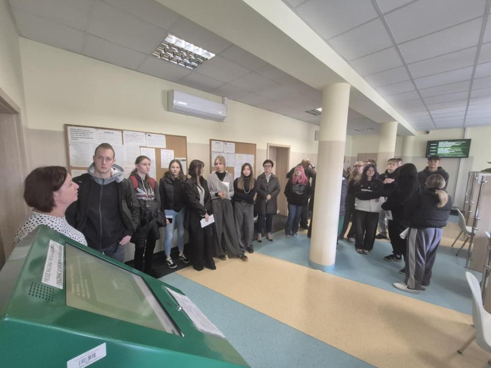 Fotografia wykonana podczas spotkania doradców zawodowych z uczniami Zespołu Szkół im. X. Dunikowskiego w  Zawierciu. Przedstawia salę wykładową a w niej grupę uczniów siedzących przy stołach i słuchających prezentacji.