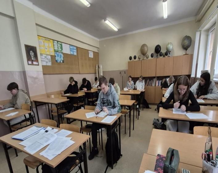 Fotografia wykonana podczas spotkania doradców zawodowych z uczniami Szkoły Podstawowej nr 13. Przedstawia sale lekcyjną a w niej młodzież pracującą przy biurkach.
