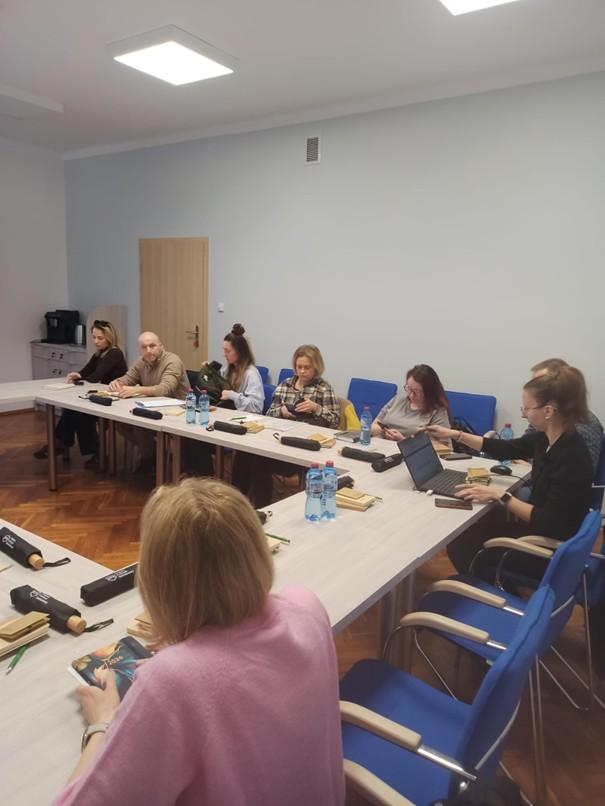 Fotografia wykonana podczas spotkania dotyczącego Krajowego Funduszu Szkoleniowego. Przedstawia sale, w której osoby zainteresowane obserwowały prezentacje dotyczącą uzupełniania wniosku KFS.