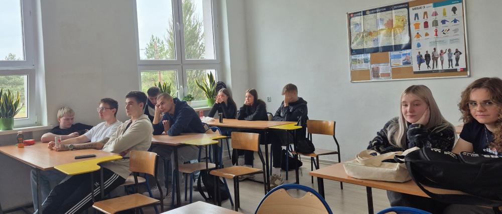 Fotografia przedstawia klasę lekcyjną a w niej uczniów siedzących przy ławkach.